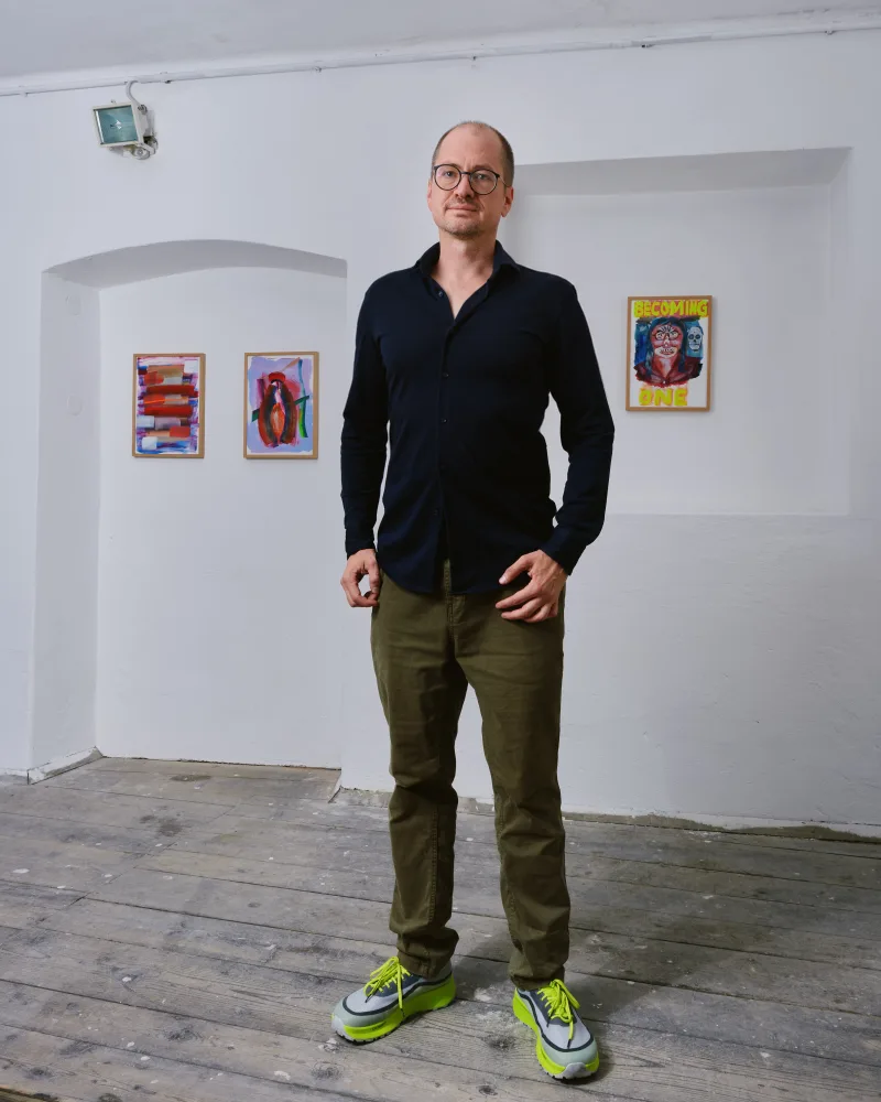 Wolf steht im Atelier vor seinen Arbeiten.